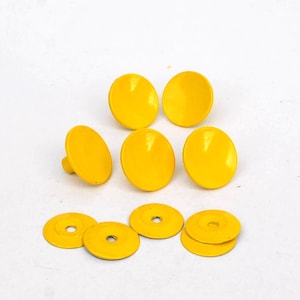 Peut inclure: Ensemble de boutons et rondelles jaune vif. Les boutons sont ronds avec une surface légèrement bombée, et les rondelles sont plates avec un trou central. Les articles sont disposés sur une surface blanche.