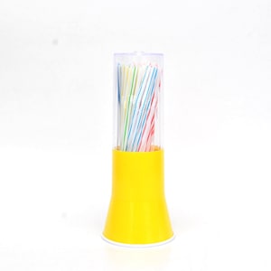 Può includere: Un portapaglia di plastica gialla con un coperchio di plastica trasparente. Il supporto contiene un fascio di cannucce a righe colorate in vari colori, tra cui rosso, blu e verde. Il supporto è su sfondo bianco.