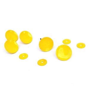 May include: A selection of bright yellow cabinet knobs and washers are arranged on a white surface. The knobs are round and have a glossy finish, while the washers are flat and circular.