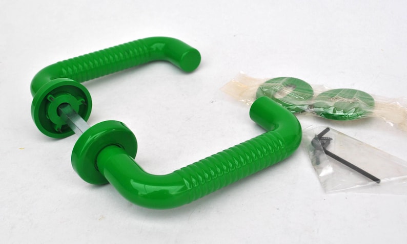 May include: Two bright green door handles with a ridged design, along with mounting hardware. The handles have a curved shape and are made of a glossy material. The hardware includes green washers and an Allen wrench.