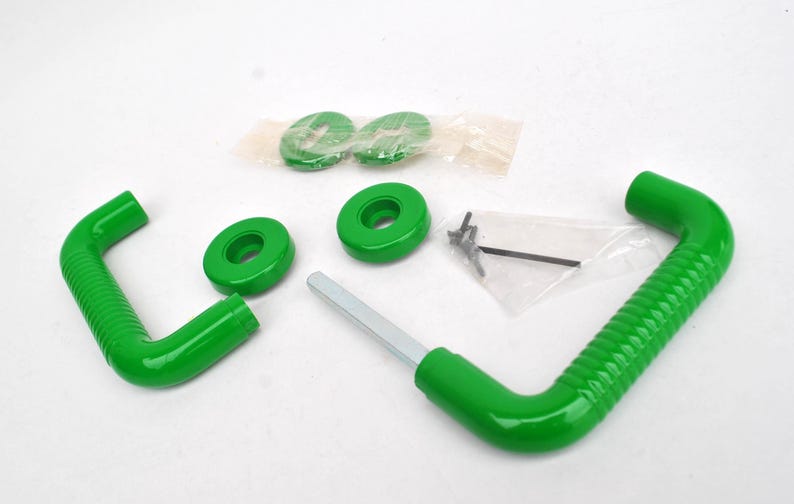 May include: An assortment of green, curved metal pieces, including two handles with textured grips, several circular components, and small screws. The parts are arranged on a white surface, suggesting a set of hardware or a component kit.