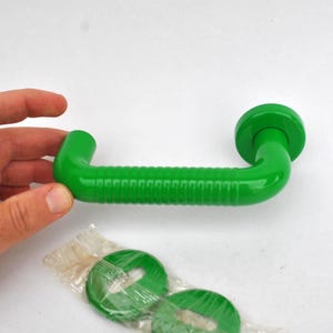 May include: Bright green, curved door handle with a ridged center section and rounded ends. Includes two matching green circular pieces, possibly for mounting. The handle is approximately 6 inches long.