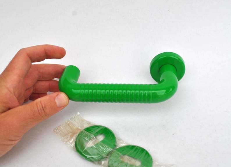 May include: Bright green, curved door handle with a ridged center section and rounded ends. Includes two matching green circular pieces, possibly for mounting. The handle is approximately 6 inches long.