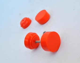 May include: A set of bright orange circular stud earrings with a smooth matte finish. One earring is assembled with a metal post, while the other two pieces are separate, showing the flat circular front and the threaded backing component.