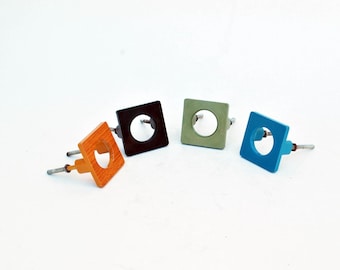 May include: Four square cabinet knobs with a circular cutout in the center. The knobs are in orange, brown, green, and blue.
