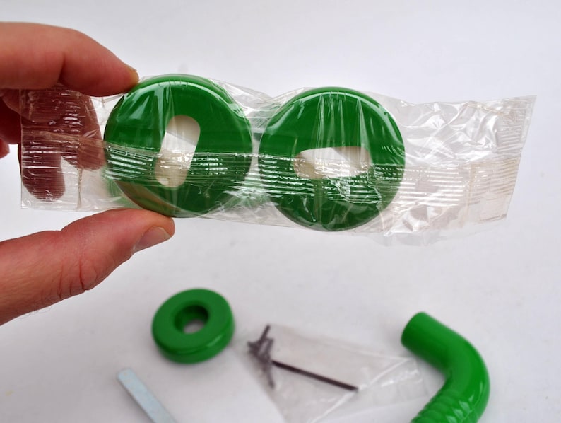 May include: A collection of green plastic parts, including two circular pieces packaged in clear plastic, a single ring, and a curved tube. Also included are small metal screws and a tool.