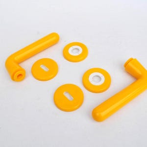May include: A set of bright yellow cabinet hardware, comprising two L-shaped handles and four round, flat pieces. The handles have a curved design, and the round pieces have a keyhole shape. The hardware is made of a glossy material.