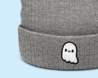 Può includere: Berretto di lana grigio con un piccolo fantasma bianco ricamato sul davanti. Il fantasma ha un viso sorridente.