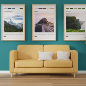 May include: Three framed travel posters with color palettes and images of Switzerland, France, and Ireland. The posters are hanging on a teal wall above a yellow couch. A potted plant is on the right side of the image.