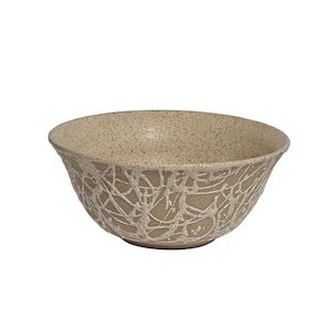 May include: A set of three ceramic mugs with a speckled, matte finish. The mugs are in shades of cream, light brown, and dark brown. Each mug has a simple, minimalist design and a rounded handle.