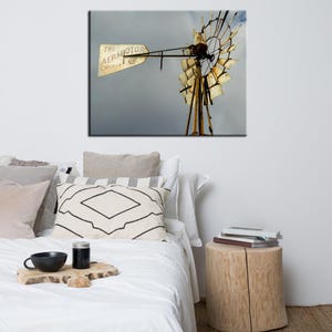 May include: A vintage windmill with weathered wooden blades and a metal frame. A sign on the windmill reads "The Aermotor Chicago". The windmill is set against a cloudy sky.