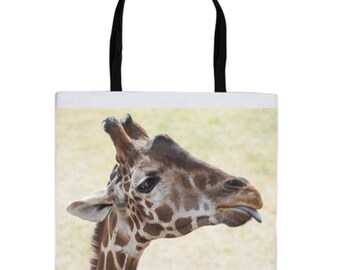 May include: A close-up of a giraffe's head and neck. The giraffe has brown and white spots and is sticking its tongue out. The background is a blurry beige color.