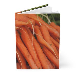 May include: A notebook with a cover displaying a close-up of a pile of fresh carrots. The image shows bright orange carrots with green tops and fine white root hairs. Ideal for those who enjoy gardening or healthy eating, the notebook's design is eye-catching.