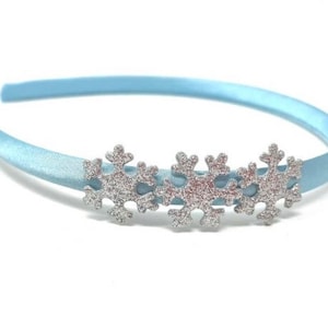 May include: A light blue satin headband with three silver glitter snowflake embellishments.
