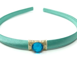 May include: A light blue satin headband with a blue gemstone accent.