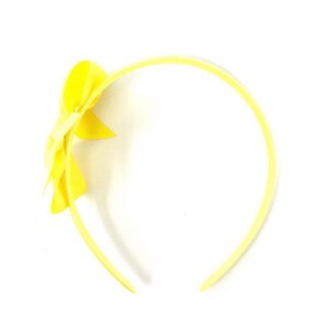 May include: A yellow headband with a yellow bow on the side.