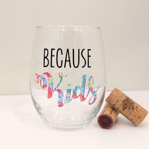 May include: A clear glass wine glass with the text "BECAUSE KIDS" printed in black. The word "KIDS" is decorated with a colorful floral pattern.