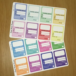 May include: A sheet of 12 colorful stickers with the text "Healthy options" and a space to write in the letter "A" and "B". Each sticker has a section to track water intake with a row of water drops and a row of stars. The stickers are in a rainbow color scheme.