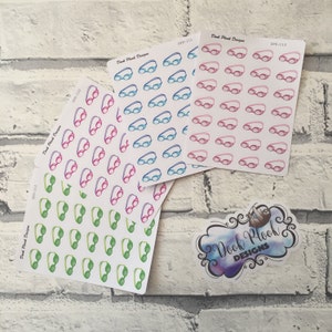 May include: Three sheets of stickers with different colored swimming goggles. The stickers are white with black outlines. The goggles are blue, pink, and green. The sheets are labeled with the text "Dook Plook Designs" and a product code.