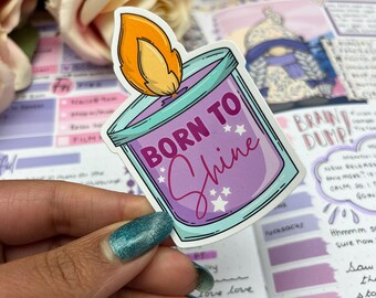 May include: A purple and blue candle sticker with a flame on top. The candle has the text "Born to Shine" in white lettering with stars around the text.