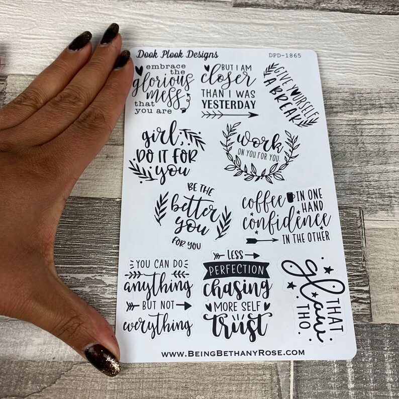 May include: A sheet of white stickers with black lettering and illustrations. The stickers feature motivational quotes such as "Embrace the glorious mess that you are", "Girl, do it for you", "Be the better you", "You can do anything but not everything", "Less perfection chasing more self trust", "Work on you for you", "Give yourself a break", "Coffee in one hand confidence in the other", and "That, too".