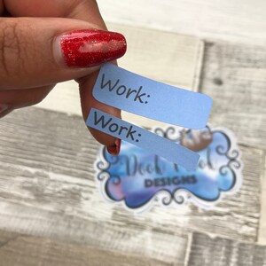 Op de afbeelding: Twee blauwe papieren tabbladen met het woord "Work:" erop geschreven in zwarte inkt.
