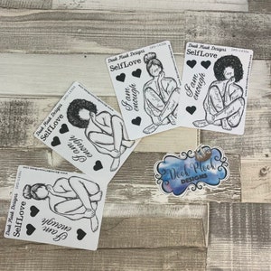 May include: Four black and white stickers with the text "Self Love" and "Fam enough" on a wooden background. The stickers feature a woman sitting with her arms wrapped around her legs. The stickers are designed to be used as motivational reminders.