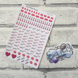 Puede incluir: Una hoja de papel adhesivo blanco con pegatinas de temática rosa y roja. Las pegatinas incluyen termómetros, corazones, labios y símbolos de pruebas de embarazo. Las pegatinas están etiquetadas con los números del 6 al 40, con las letras CD y DPO. La hoja también incluye el texto "Dook Plook Designs" y "DPD-398".