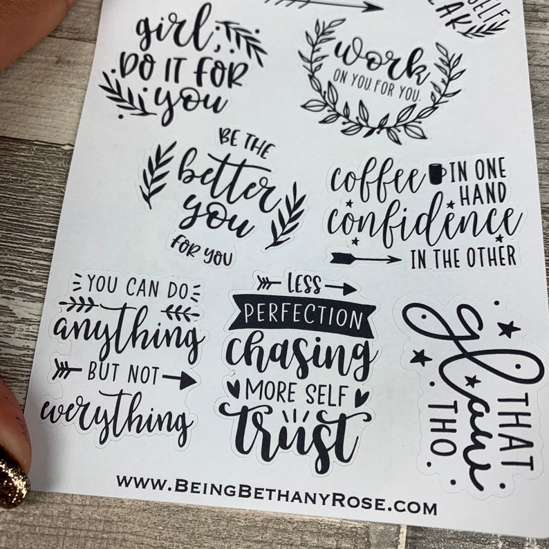 May include: A sheet of black and white stickers with motivational quotes and phrases. The stickers feature a variety of fonts and designs, including floral elements, arrows, and stars. Some of the quotes include "Girl, do it for you", "Work on you for you", "Be the better you", "Coffee in one hand, confidence in the other", "You can do anything but not everything", "Less perfection chasing more self trust", and "That, thou".