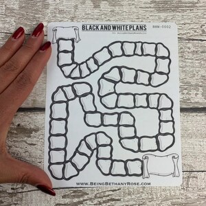 May include: Black and white printable game board with a winding path made of stone blocks. The board has two scroll banners at the top and bottom. The text "BLACK AND WHITE PLANS" and "BNW-0002" is printed at the top of the board. The text "www.beingbethanyrose.com" is printed at the bottom of the board.