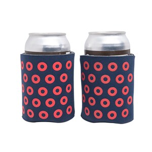 May include: Two aluminum cans in navy blue can coolers with a repeating pattern of red circles. The coolers are designed to keep beverages cold and are suitable for outdoor events or casual gatherings.