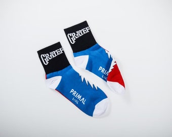 May include: A pair of blue, red, and white socks with the words "GRATEFUL" and "PRIMAL" printed on them. The socks are designed with a lightning bolt pattern.