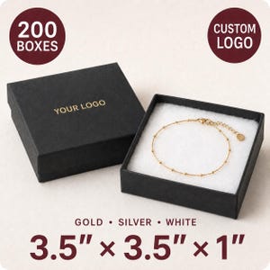 May include: A black square jewelry box with the text YOUR LOGO in gold, containing a delicate gold chain bracelet with small beads. The box measures 3.5 inches by 3.5 inches by 1 inch. The set includes 200 boxes available in gold, silver, or white.