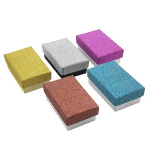 May include: Six small gift boxes with glitter finishes in various colors, including gold, silver, pink, blue, and red. The boxes are all the same size and shape, and they are arranged in a row.