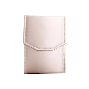May include: A pale pink, rectangular jewelry box with a flap closure and a subtle textured finish.
