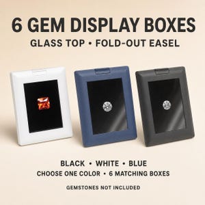 May include: Six rectangular gem display boxes with glass tops and fold-out easels, available in white, blue, or black. Each box features a black interior lining. Text reads: 6 GEM DISPLAY BOXES, GLASS TOP, FOLD-OUT EASEL, BLACK, WHITE, BLUE, CHOOSE ONE COLOR, 6 MATCHING BOXES, GEMSTONES NOT INCLUDED.