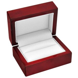May include: A red wooden ring box with a white velvet interior. The box is open and the lid is propped up.