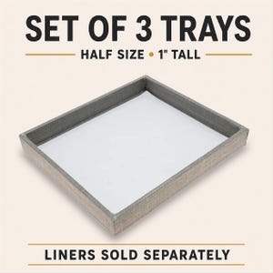 May include: A set of 3 trays with a rectangular shape, featuring a light gray textured exterior and a smooth white interior base. The text SET OF 3 TRAYS, HALF SIZE, 1 INCH TALL, and LINERS SOLD SEPARATELY is displayed in black and gold.