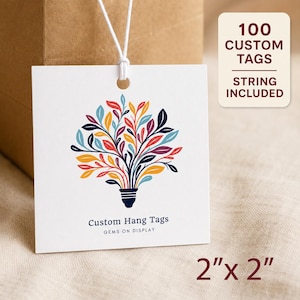 May include: A square white hang tag with a white string, featuring a colorful graphic of a lightbulb with leaves as the filament. The text reads Custom Hang Tags and GEMS ON DISPLAY. A label indicates 100 CUSTOM TAGS STRING INCLUDED and 2" x 2".