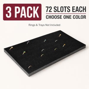May include: A black rectangular jewelry display insert featuring 72 slots for rings. The text 3 PACK 72 SLOTS EACH CHOOSE ONE COLOR is displayed above the insert, with the note Rings & Trays Not Included. The insert is shown with several rings.