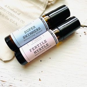 May include: Two small glass bottles with black roll-on tops. The bottles are labeled "Super Swimmers fertility blend" and "Fertile Myrtle fertility blend".