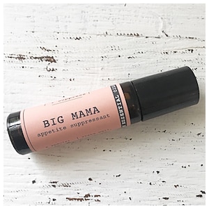 Puede incluir: Un frasco de aceite esencial de rodillo rosa y negro con el texto "BIG MAMA appetite suppressant" en la etiqueta.