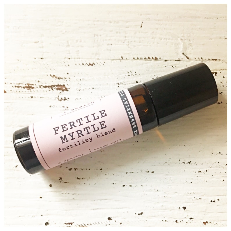 May include: A small brown glass roller bottle with a black cap and a pink label that reads "Fertile Myrtle fertility blend".
