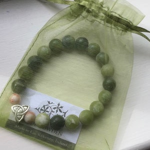 May include: A green jade stone bracelet with a silver Celtic knot charm. The bracelet is in a green organza bag with a tag that reads "Made in Co. Kilkenny, Ireland".