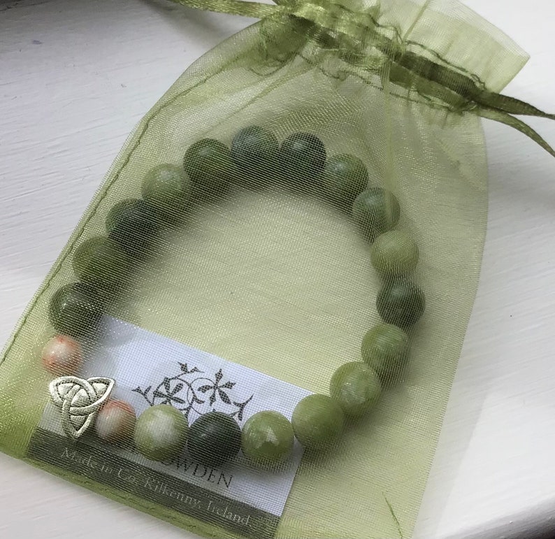 May include: A green jade stone bracelet with a silver Celtic knot charm. The bracelet is in a green organza bag with a tag that reads "Made in Co. Kilkenny, Ireland".