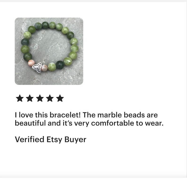 May include: A green marble bead bracelet with a silver Celtic knot charm. The bracelet is on a gray background.