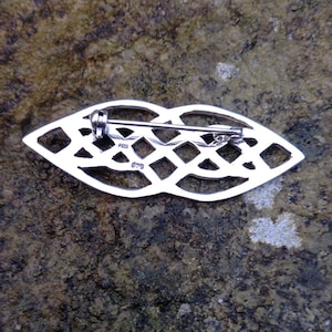 Pode incluir: Broche de n&oacute; celta de prata com um pino na parte de tr&aacute;s. A parte de tr&aacute;s da broche &eacute; marcada com os n&uacute;meros "925" e "079".