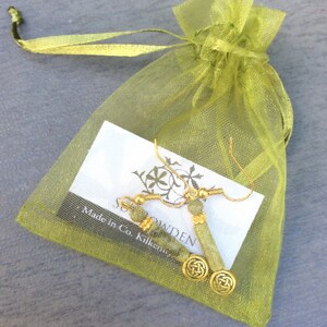 May include: A pair of gold earrings with Connemara marble beads and a Celtic knot design. The earrings are in a green organza bag with a white card that reads 'Made in Co. Kilkenny'.