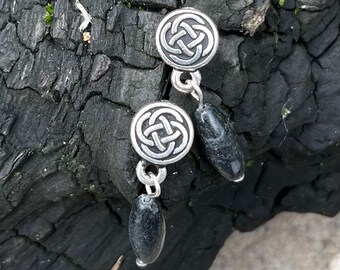 May include: A pair of silver earrings with a Celtic knot design and black stone accents.