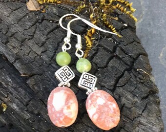 May include: A pair of dangle earrings with a pink and white oval stone, a silver charm, and a green bead.